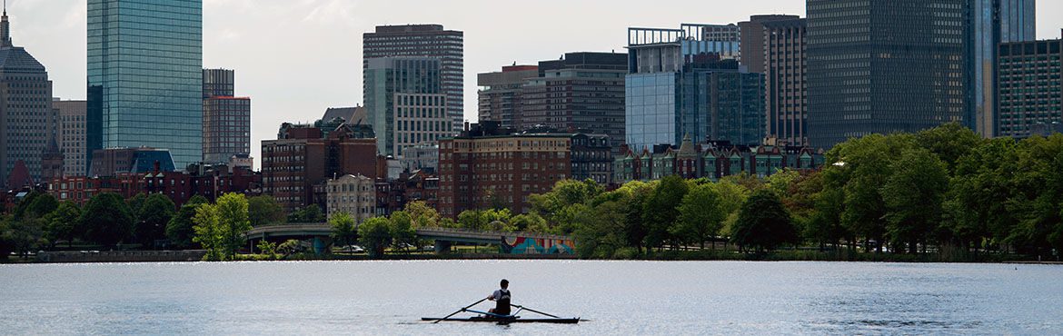 Lone rower on the Charles River with Boston skyline in the background.