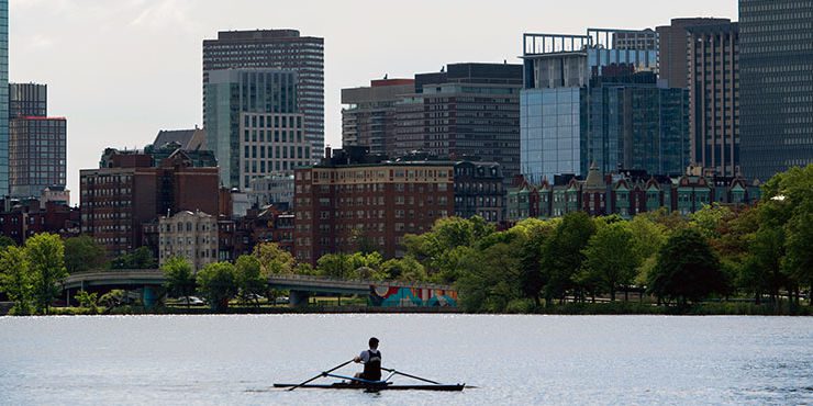 Lone rower on the Charles River with Boston skyline in the background.