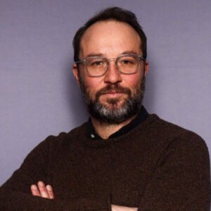 Dan Mauzy, wearing glasses, serious portrait with arms folded.